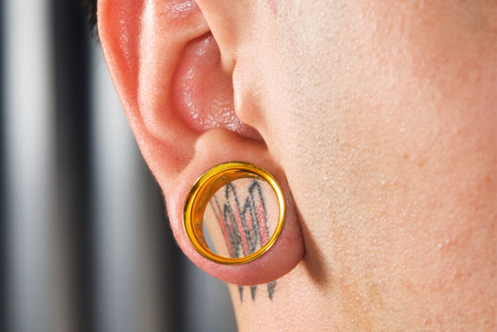 Close-up of a young mans ear with gold gauge in earlobe