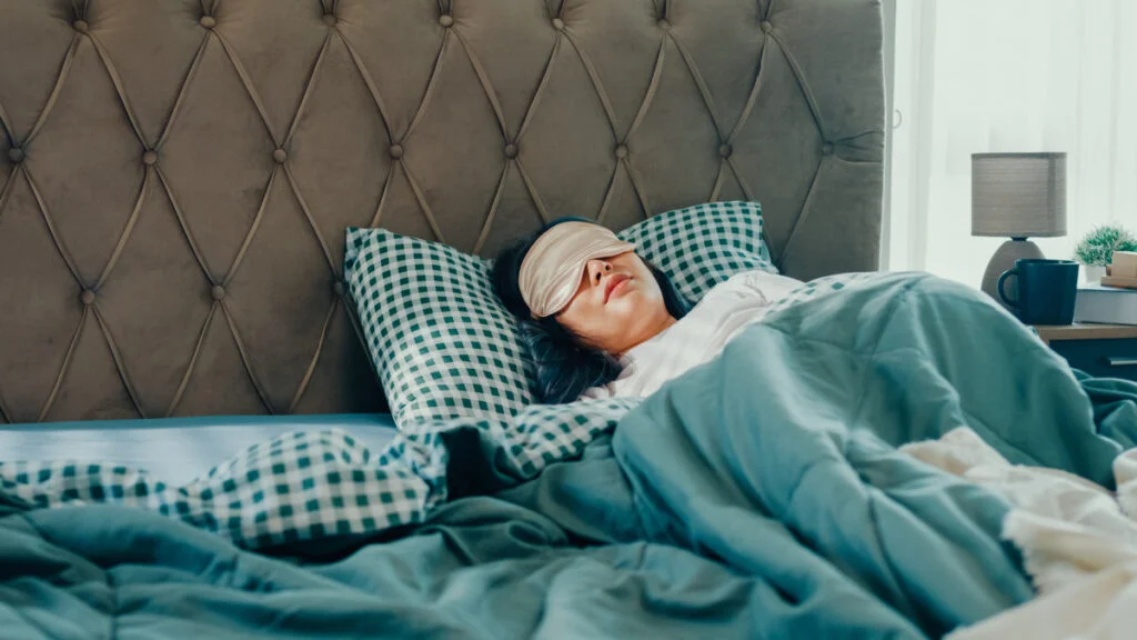 Woman fast asleep in bed with silk eye mask
