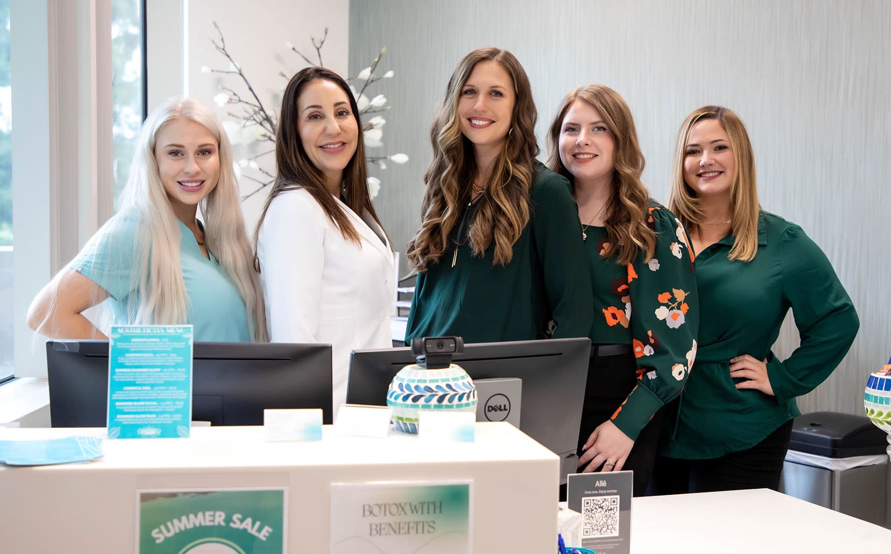 Group photo of staff smiling behind front desk