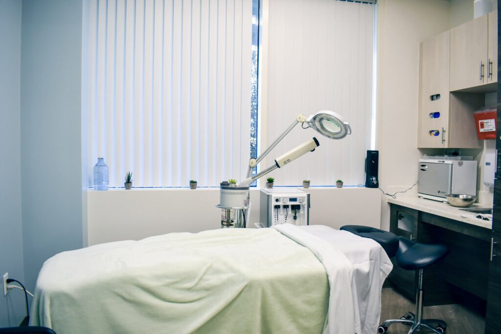 Aesthetician services treatment room with a table covered in clean blankets and a light over the head of the bed.