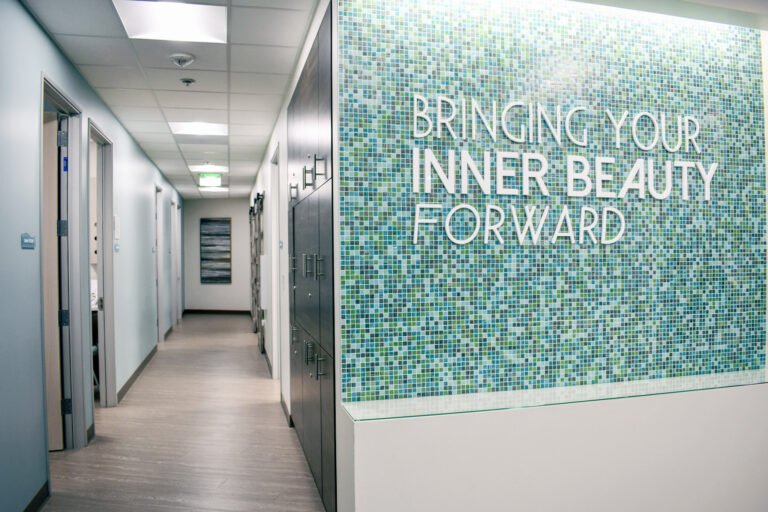 Office wall with slogan, “Bringing your inner beauty forward,” before hallway leading to treatment rooms and surgery center.