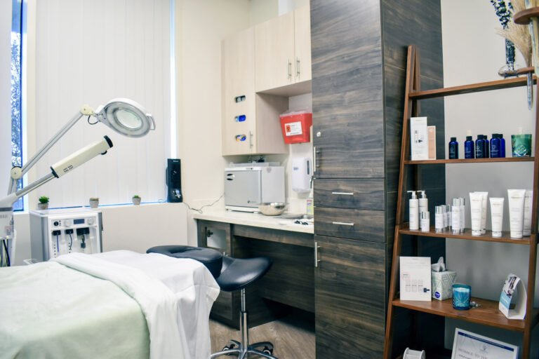 Facial services room with skincare products shelf and treatment table.