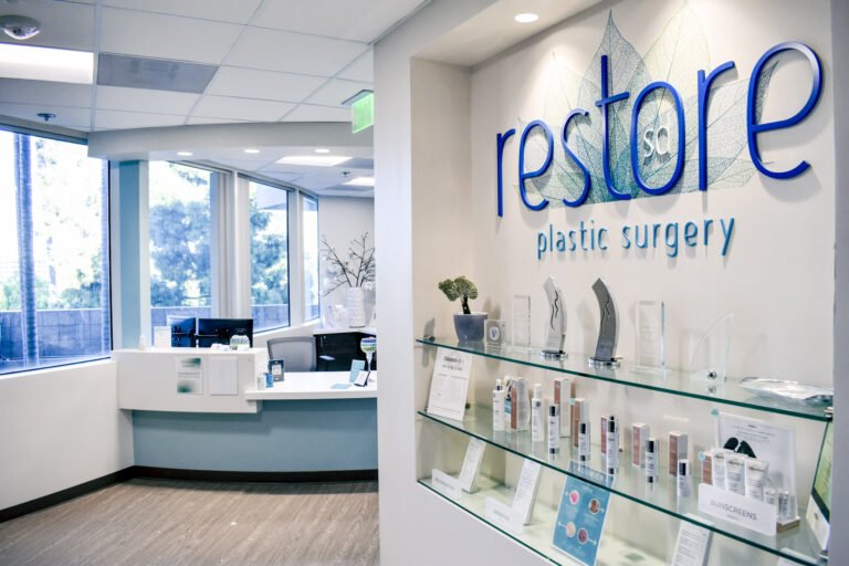 Entrance to Restore SD Plastic Surgery, brightly lit with medical-grade skincare products lining the wall and reception desk.