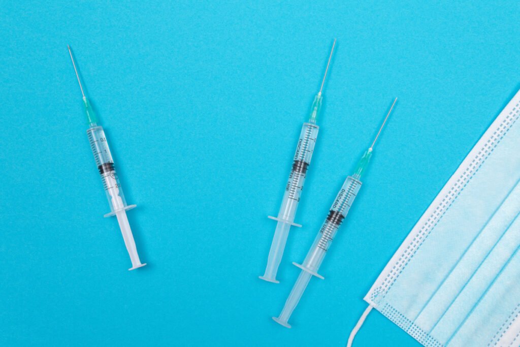 Cosmetic injectable syringes laying on a table next to a surgical mask