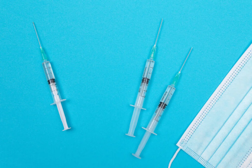 Cosmetic injectable syringes laying on a table next to a surgical mask