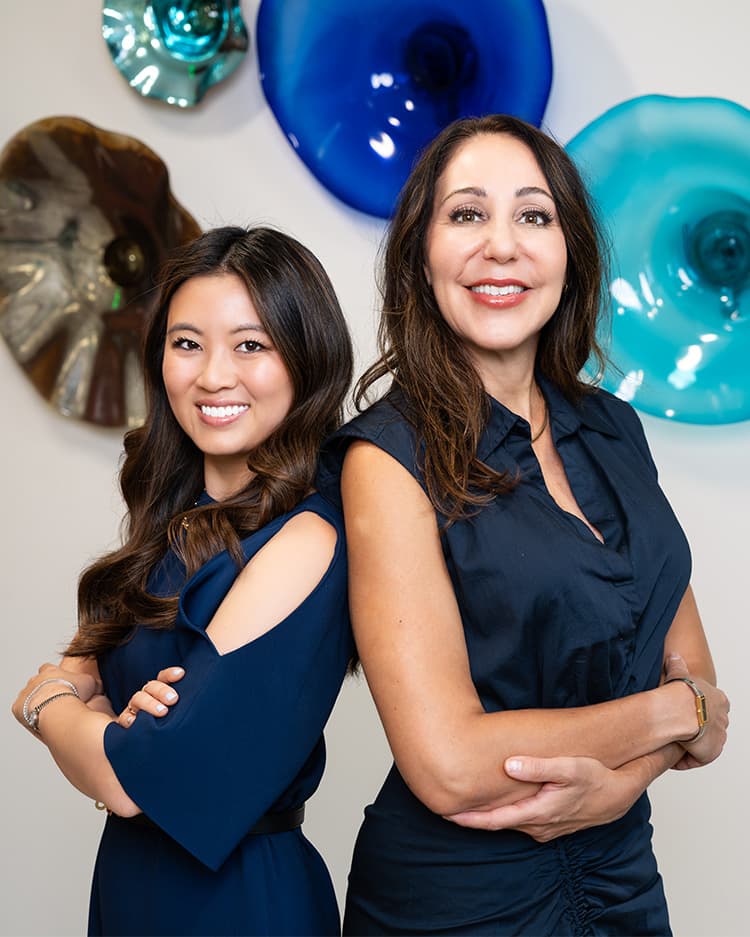 Dr. Janet Chao and Dr. Katerina Gallus smiling, standing back to back with their arms crossed