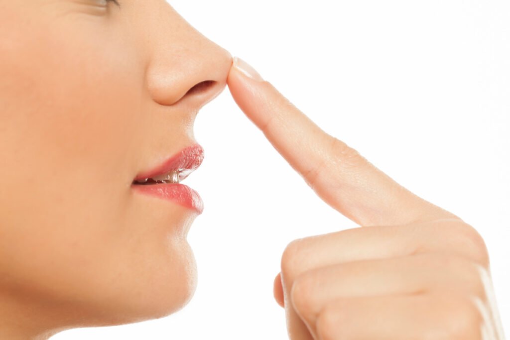 Close up of woman poking tip of her nose against white studio background