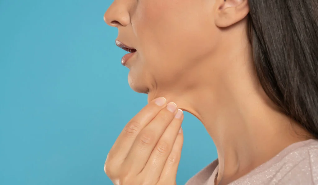 Close up profile view of woman pinching extra skin on neck
