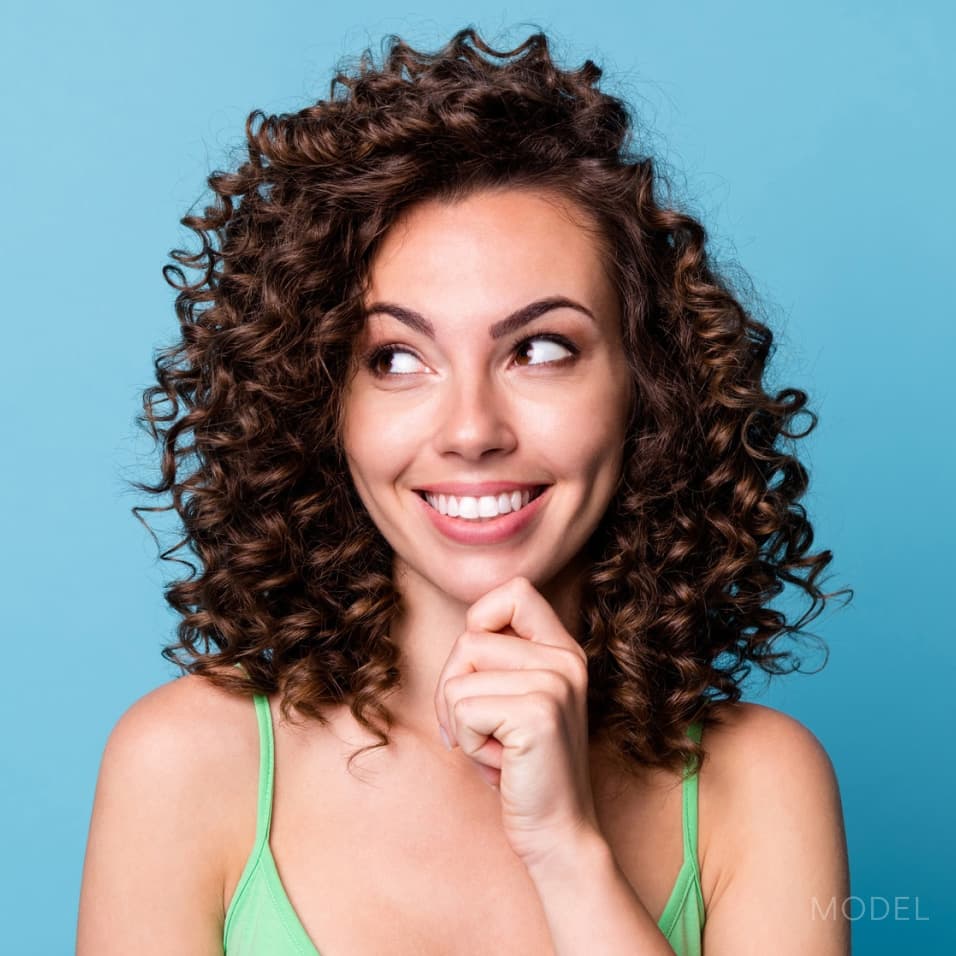 Close up of woman's forehead and high hairline against blue background