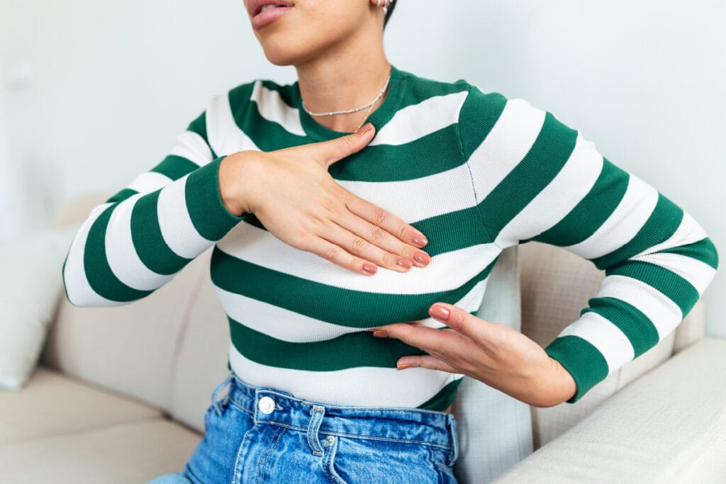 Faceless woman in striped shirt performing self breast exam