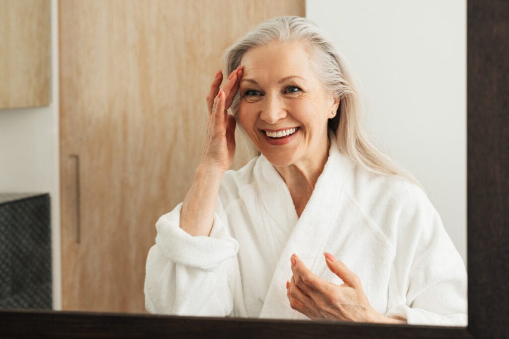 Mature woman looking at deep plane facelift results in the mirror