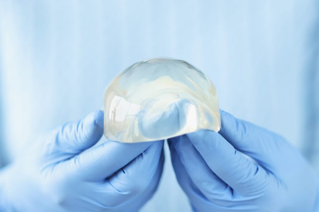 Gloved hands holding silicone breast implant